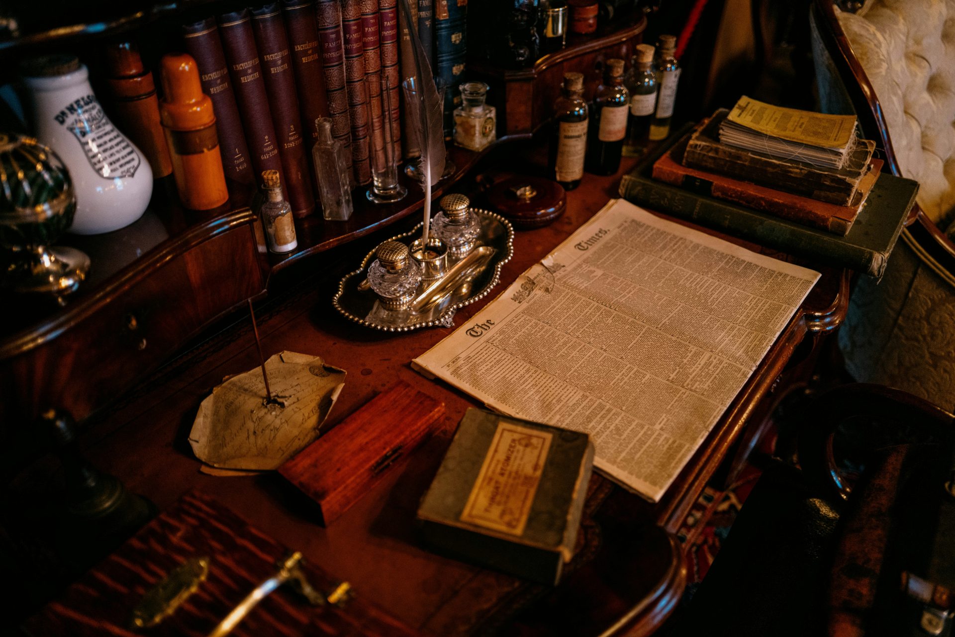 Alter Schreibtisch mit Büchern, Tintenfass und Papieren.